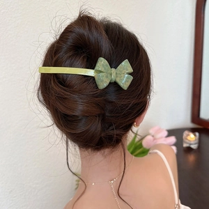 Vue détaillée d'une pince à cheveux nœud 3D vert clair en acétate dans une coiffure