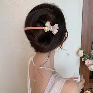Gros plan d'une pince à cheveux nœud en acétate corail et marbre sur un modèle