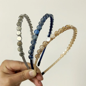 Detailed view of three slim headbands with faceted glass beads in navy, gold, and taupe