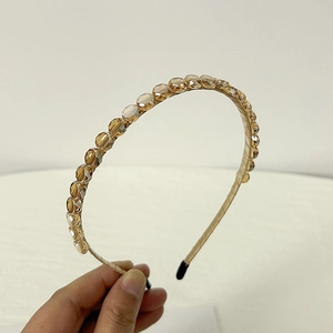 Detail of amber crystal headband featuring hand-wrapped champagne satin and metal frame