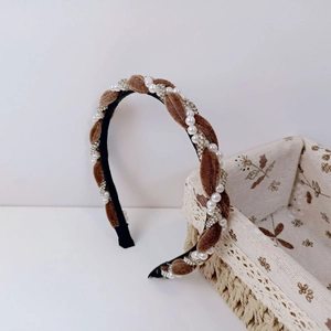 Detail of twisted brown velvet headband with sparkling crystals and white faux pearls