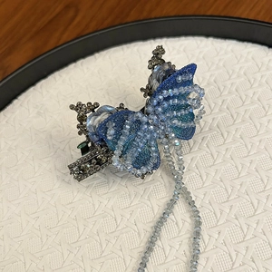 Dettaglio del fermaglio per capelli a farfalla con perline blu, strass e nappe