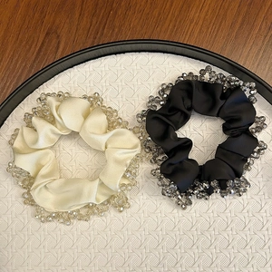 Detailed close-up of champagne and black satin scrunchies with crystal bead edging