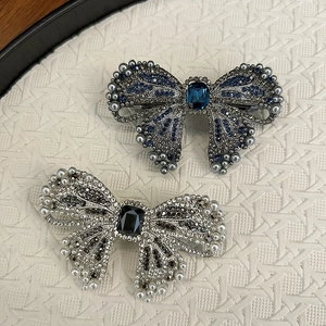 Elegant bow hair clip with vintage rhinestones and pearls on a white tray