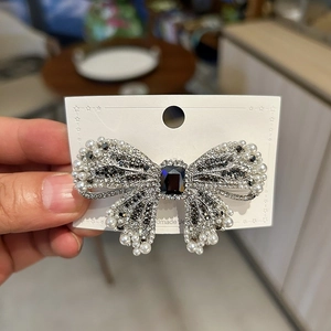 Elegant bow hair clip with sparkling rhinestones and black gemstone on display card