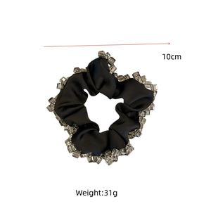 Détail d'un chouchou noir en satin de 10cm orné de perles de cristal sur les bords