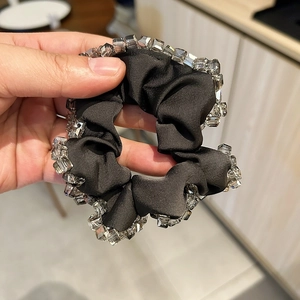 Détail d'un chouchou en satin noir orné de perles de cristal carrées très élégantes