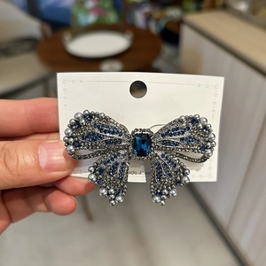 Detail of luxury bow hair clip with navy crystals and blue center stone on handmade card