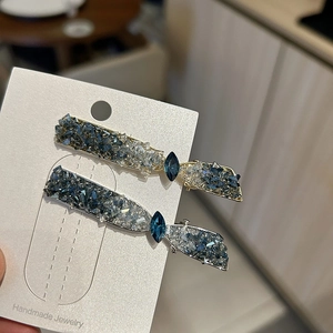 Gros plan de barrettes faites main avec cristaux bleus et gris sur carte de support
