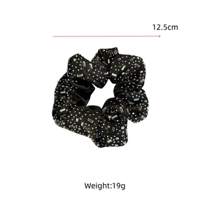 Détail d'un chouchou en velours noir avec strass montrant 12,5 cm de diamètre et 19 g de poids