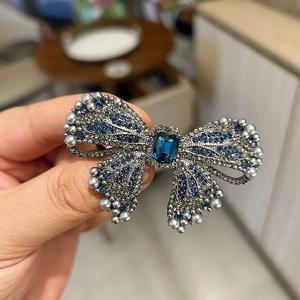 Detailed view of luxury navy blue bow hair clip with crystals and grey pearls decoration