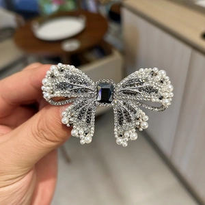 Macro detail of luxury bow hair clip with black rhinestones and pearl edge