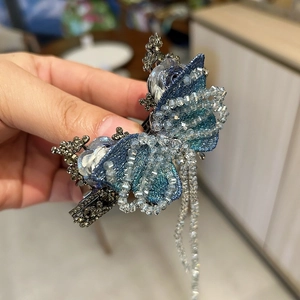Dettaglio del fermaglio per capelli a farfalla blu con perline di cristallo e nappe lunghe