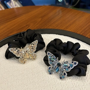 Close-up of champagne and blue crystal butterfly hair ties on a black satin band