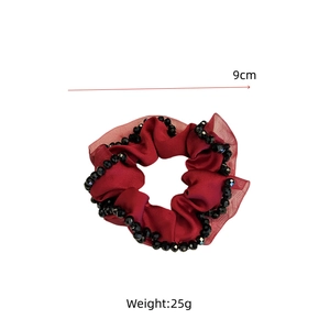 Detail of red satin scrunchie with hand-stitched crystal beads and 9cm diameter size mark