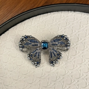Detail of luxury bow hair clip with navy blue crystals and grey pearls on silver base