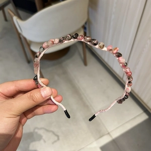Detailed shot of pink stone beads hand-woven onto a slim headband with protective tips