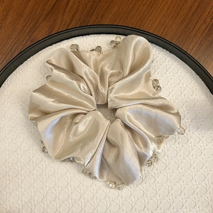 Elegant champagne gold satin scrunchie with crystal beads on a white tray