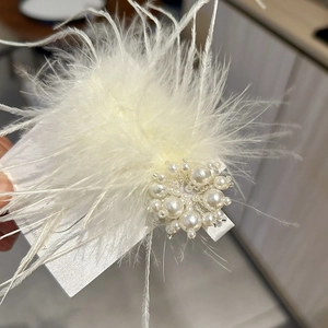 Elegant white feather hair clip with pearl cluster on a minimalist display card
