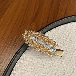 Detailed close-up of handmade luxury hair clip with champagne crystals on a gold base