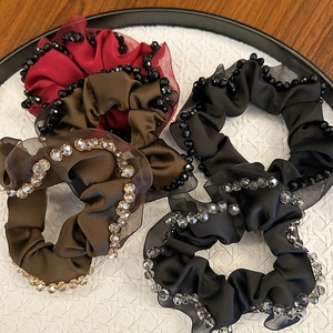Handmade satin scrunchies with crystal trim in red, coffee, and black on a tray