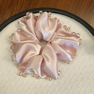 Detailed view of pink satin scrunchie with faceted amber crystal beads decoration