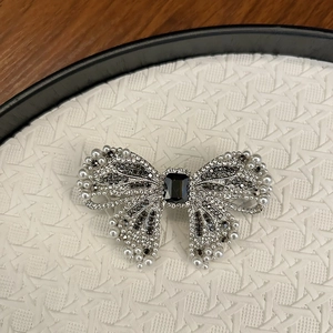 Macro shot of silver bow hair clip with black crystal center and white pearl accents