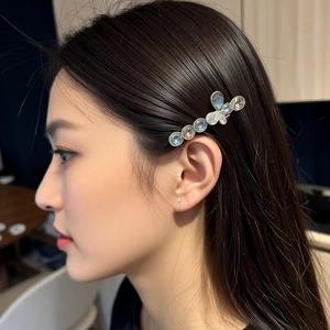 Elegant crystal bow hair clip with blue rhinestones worn by a model in a warm setting