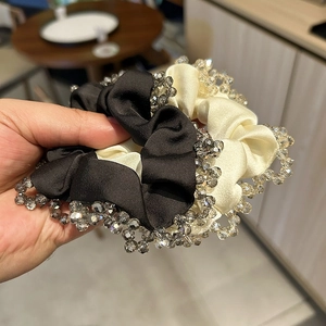 Detail of satin scrunchie featuring hand-sewn grey crystal beads and pleated fabric