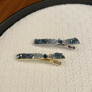 Gros plan de pinces à cheveux artisanales avec cristaux bleus et détails en strass