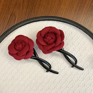 Elegant pair of red velvet flower hair claws with black twisted clips on a tray