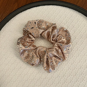 Chouchou élégant en satin doré champagne avec strass scintillants dans un plateau