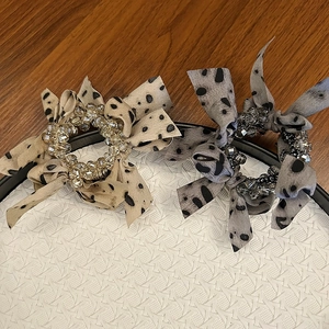 Detail of leopard print mesh bow hair clips with crystal beads on a woven tray
