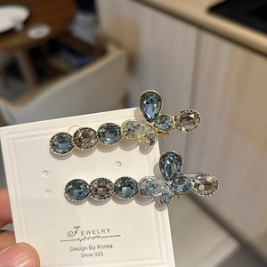 Detailed macro view of two luxury crystal bow hair clips with blue and silver gemstones
