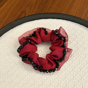 Elegant burgundy satin scrunchie with crystal beads on a white tray backdrop
