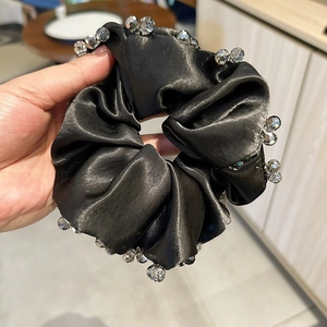 Detailed view of luxury black satin hair scrunchie with sparkling crystal bead embellishments