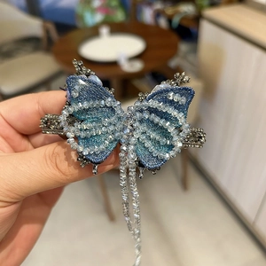 Dettaglio del fermaglio per capelli a farfalla blu con perline e lunghe nappe