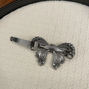 Elegant silver butterfly hair clip with crystal metal mesh on a white textured tray