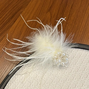 Detail of white feather hair clip with lustrous faux pearls and metal alligator base
