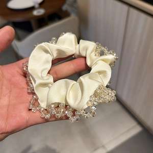 Close-up of cream satin scrunchie with sparkling crystal beads and lace edge