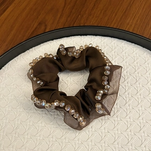 Detail of dark brown satin scrunchie with champagne faceted crystal beads on display