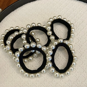Élastiques à cheveux noirs avec perles blanches artificielles sur plateau blanc