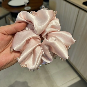 Close-up of pink satin scrunchie featuring elegant faceted bead trim for a luxury feel
