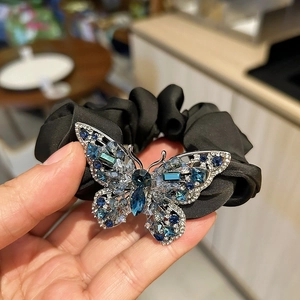 Detail of luxury black satin hair tie featuring a large butterfly with blue rhinestones