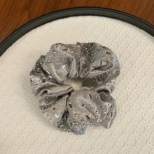Détail d'un chouchou en velours gris argenté avec des strass étincelants exposés