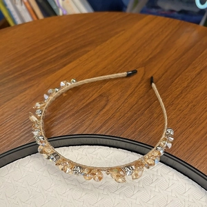 Détail d'un serre-tête en cristal doré champagne avec fil tissé et grappes de strass