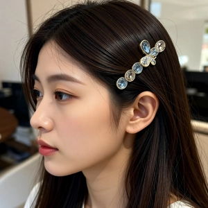 Close-up of a high-end crystal bow hairpin worn by a model in soft lighting