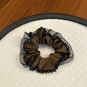 Detail of silk satin hair scrunchie with pleated mesh lace and black crystal beads