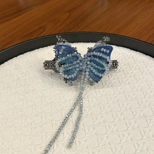 Dettaglio del fermaglio per capelli a farfalla blu ricamato con nappe di cristallo e metallo