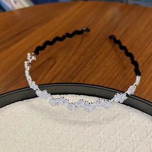Détail de cristaux en marquise sur un serre-tête argenté avec base noire ondulée